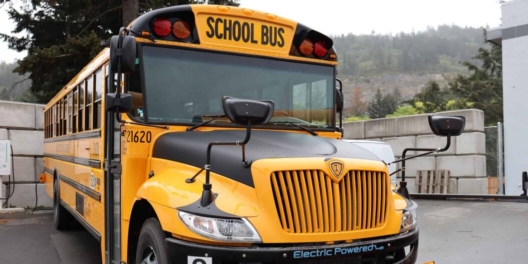 A closeup of the front of a new electric school bus on a cloudy day.