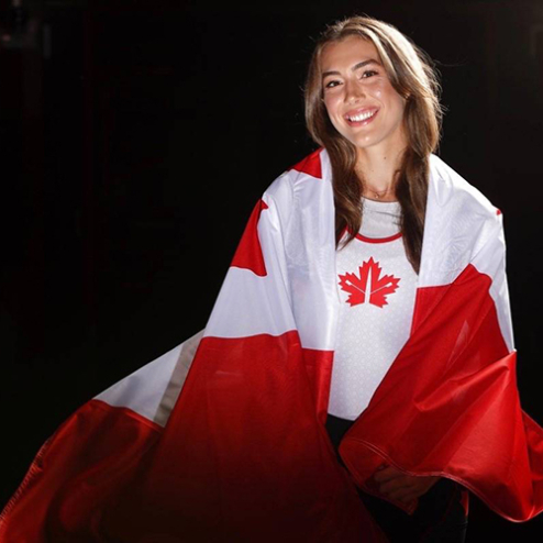 A portrait of Avalon Wasteneys wearing a Canadian flag like a cape.