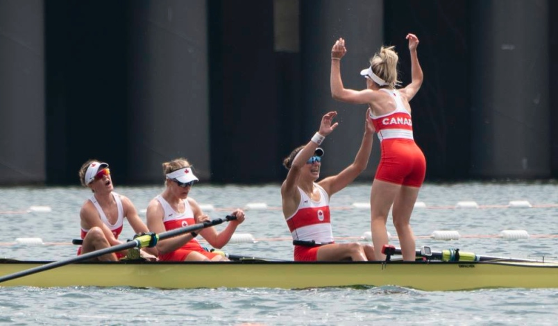Three of the eight rowers and the coxswain celebrate right after winning the gold medal race.