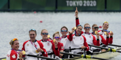 The Canadian Women's 8 rowing team in a row boat holding up their gold medals.