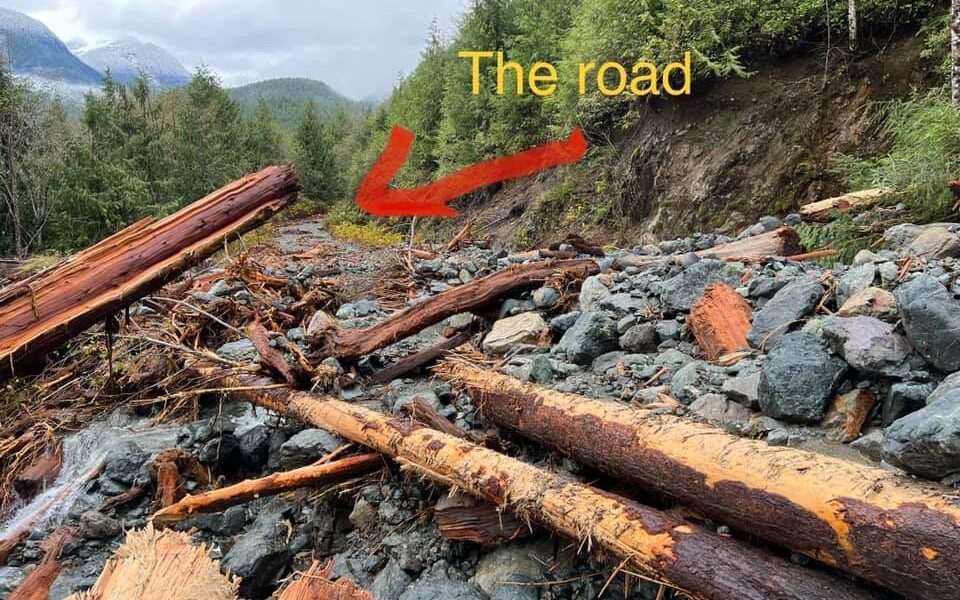A picture of rocks and logs that have slid down the mountain and covered the road.