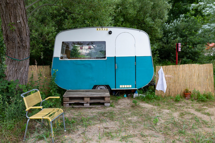 A little camper sits on palettes. The bottom is blue and the top is white. It's not attached to a vehicle.