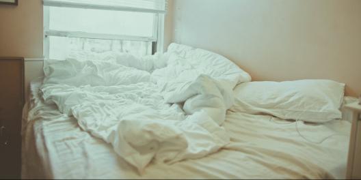 A bed with white linens in a sunny room.