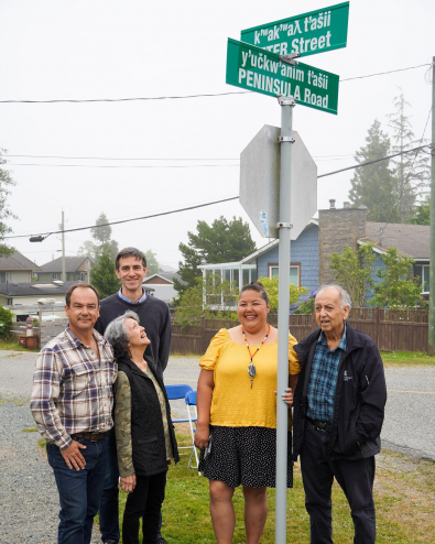 Jeneva Touchie stands with a group of smiling onlookers at the new Bilingual street signs in Ucluelet.