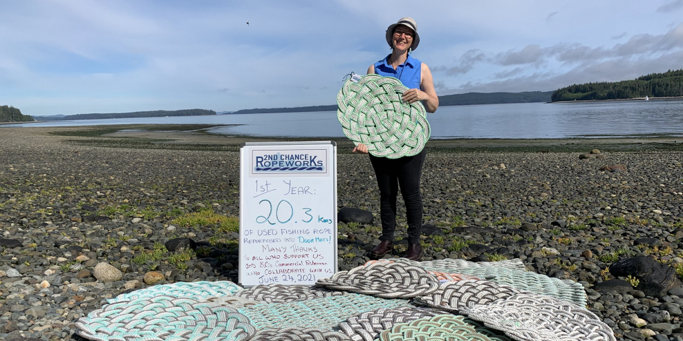 Joy Moody holds one of her mats with a sign that says 20 kilometres of rope have been reused in her creations.
