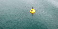 A yellow smart buoy bobs alone in the ocean.