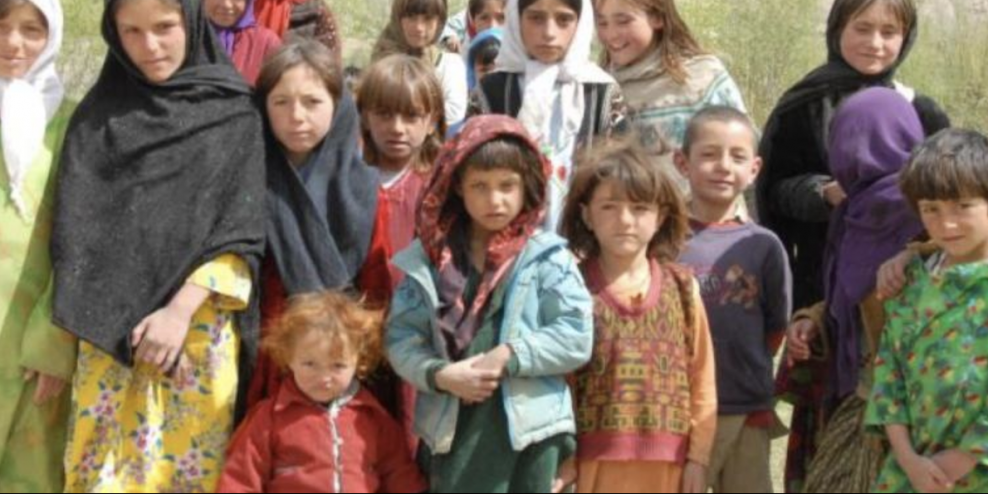 A group of Afghan children stands together for a photograph.