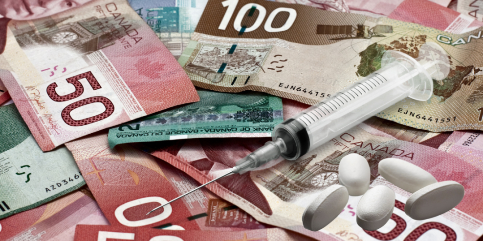 A syringe and some pills sit on top of a pile of Canadian cash.