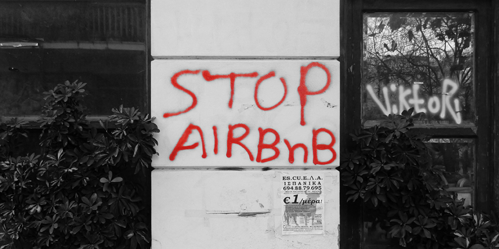 Spray paint graffiti on the wall that reads STOP AIRBNB.
