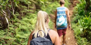 Two young people hike on a well-maintained wooded trail.