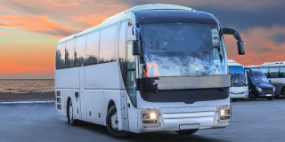 A tour bus parked against a sunset.