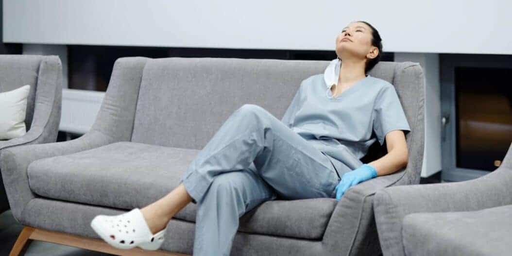 Photo of a tired healthcare professional resting on a grey couch