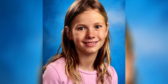 A school photo of Alexandra. She is wearing a light pink shirt and has long blond hair that is parted in the middle.