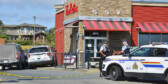 RCMP officers stand outside a Tim Horton's on a sunny day.