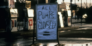 A handmade sign out front of a gas station that reads "All pumps closed".