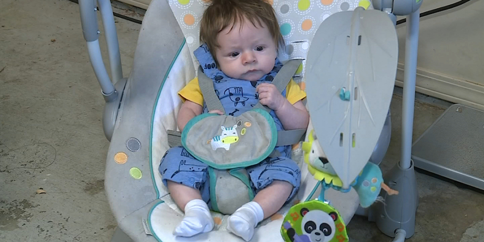 Baby λugʷaləs sits in a bouncy chair.