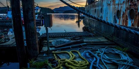 Early morning light hits coiled fishing ropes on a dock with hills in the background.