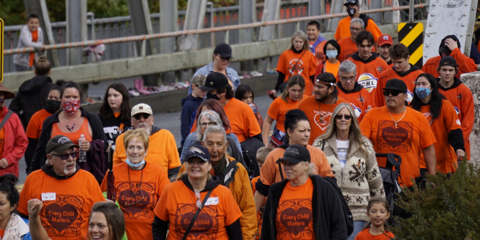 A group of folks wearing orange shirts walk in Port Alberni.