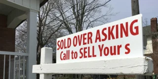 A house for sale sign that says "sold over asking."