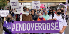 Folks involved with Moms Stop the Harm stand with signs that read "end overdose."