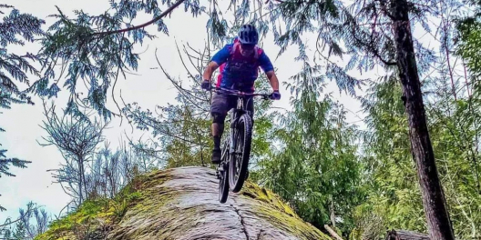 A man on a mountain bike comes flying down a rockface.